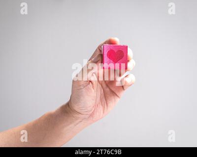 Main tenant une boîte rouge en forme de coeur. Charité, don ou concept d'amour. Banque D'Images