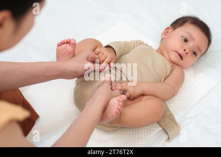 mère avec son bébé en bas âge pendant le changement de vêtements Banque D'Images