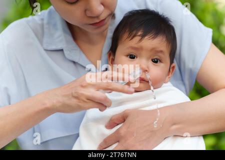 mère faisant le lavage nasal pour son bébé avec seringue et solution saline. nettoyer le nez de bébé Banque D'Images