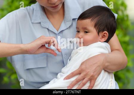 mère faisant le lavage nasal pour son bébé avec seringue et solution saline. heureux nettoyage du nez de bébé Banque D'Images