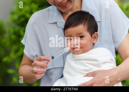 mère faisant le lavage nasal pour son bébé avec seringue et solution saline. heureux nettoyage du nez de bébé Banque D'Images