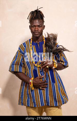 Portrait d'un jeune homme africain avec des dreadlocks et élégamment vêtu d'un vêtement coloré typique. Expression sérieuse et regardez la caméra Banque D'Images