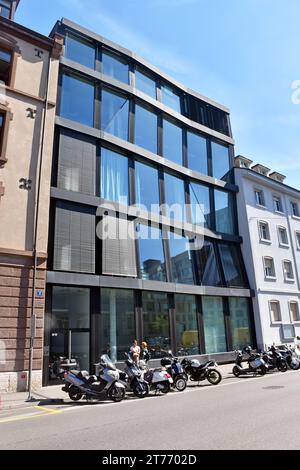 Bâtiment à ossature d'acier, façade plate, 6 baies, 5 étages, 1 portes & 29 grandes feuilles de verre, cadre subtilement déformé, de façon légèrement troublante. Banque D'Images