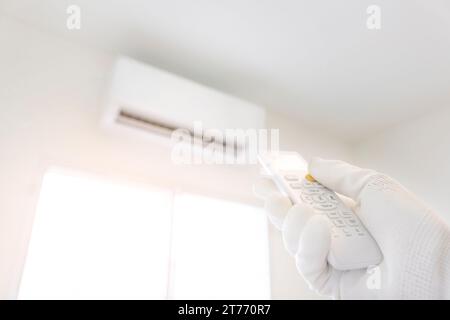 La main d'ingénierie utilise la télécommande pour allumer-éteindre le climatiseur dans le salon blanc Banque D'Images