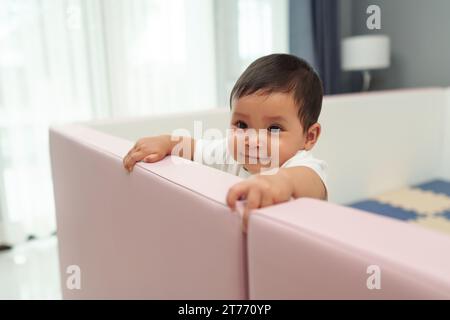 bébé bébé heureux debout dans une clôture de parc Banque D'Images