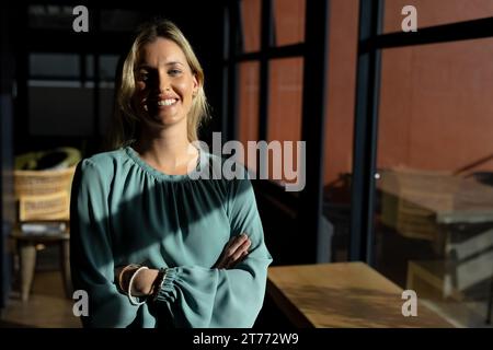 Portrait de blonde caucasienne femme d'affaires occasionnelle souriant au soleil au bureau, espace de copie Banque D'Images
