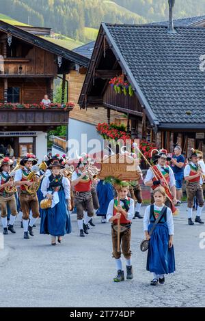 Un jeune garçon et une jeune fille dirigent un groupe de musique d'Alpbach Autriche, en robe tyrolienne traditionnelle, marchant dans le centre de la ville, jouant des instruments. Banque D'Images