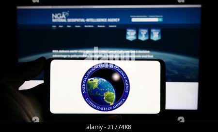 Personne tenant un smartphone avec le sceau de la National Geospatial-Intelligence Agency (NGA) des États-Unis devant le site Web. Concentrez-vous sur l'affichage du téléphone. Banque D'Images