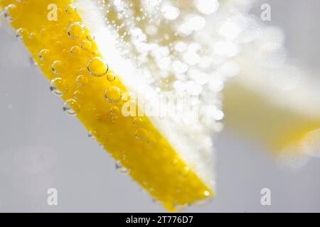 Extreme close up d'une tranche de citron flottant dans l'eau pétillante Banque D'Images