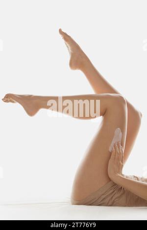 Woman Applying Lotion pour le corps sur les jambes Banque D'Images