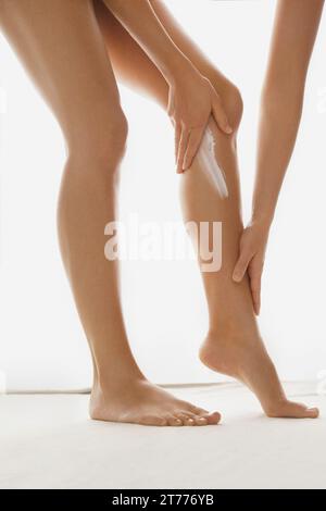 Woman Applying Lotion pour le corps sur les jambes, Low Section Banque D'Images