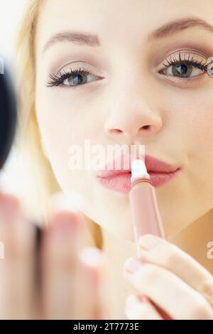 Close up of Young Woman Applying Lip Gloss Banque D'Images