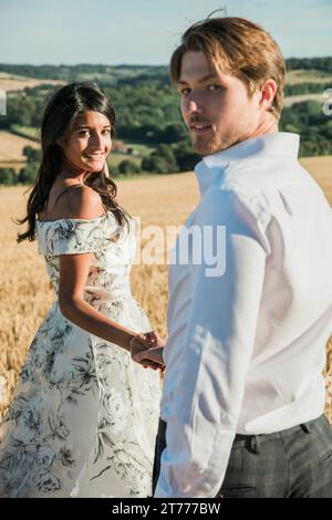 Couple dans un champ Holding Hands Banque D'Images