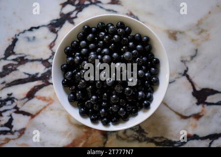 Vue d'en haut nature morte chokeberries noires dans le bol sur le comptoir de granit Banque D'Images