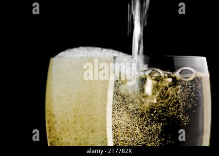 verres pleins de champagne et un étant rempli sur fond noir Banque D'Images