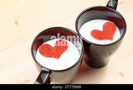 deux tasses de lait avec des coeurs décoratifs sur la table en bois avec espace pour le texte, concept de saint valentin Banque D'Images