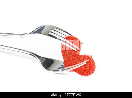 coeur rouge décoratif près des fourchettes sur fond blanc avec espace pour le texte, concept dîner de saint-valentin Banque D'Images