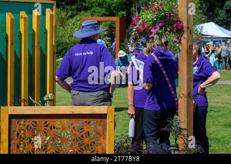 4 femmes volontaires debout ensemble pour parler par le concours Empowerment Garden - Sunny RHS Tatton Park Flower Show 2023, Cheshire, Angleterre Royaume-Uni. Banque D'Images