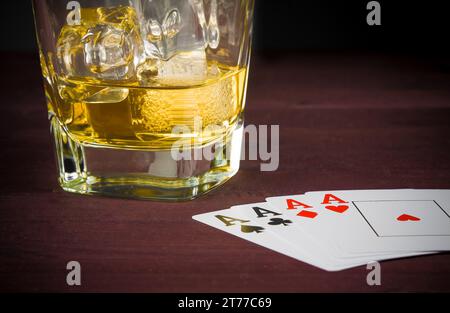 poker jouer aux cartes près du verre wiskey sur la vieille table en bois Banque D'Images