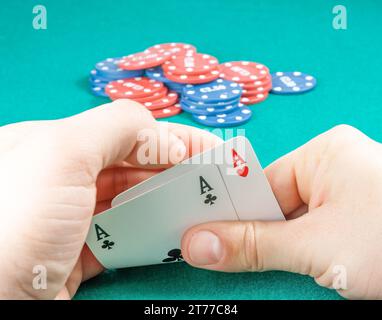 gagner des cartes à jouer dans les mains d'un homme près des fiches sur la table de jeu Banque D'Images