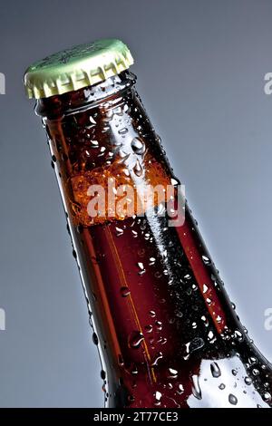 une bouteille de bière fraîche avec gouttes, isolée sur fond gris Banque D'Images