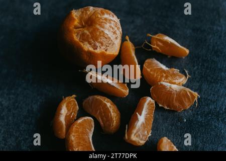 Un gros plan de deux oranges mûres sur une table en bois, dont l'une a été pelée et coupée en deux, révélant son intérieur juteux Banque D'Images