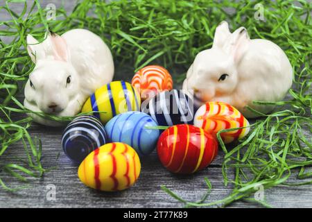 Figurines de lapin avec des œufs de Pâques sur gris Banque D'Images
