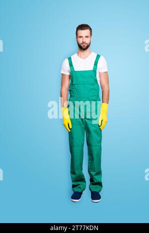 Portrait complet de la belle femme de ménage concentrée barbu avec barbe de 3 jours, coiffure en uniforme vert, isolée sur gris Banque D'Images