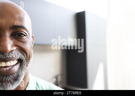 Demi-portrait d'homme mûr afro-américain chauve heureux avec barbe souriant dans une chambre ensoleillée, espace de copie Banque D'Images