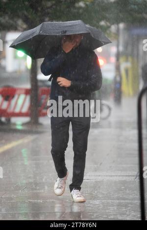 Les gens marchent sous la pluie près du Home Office dans le centre de Londres. Une semaine de pluie pourrait tomber en quelques heures à travers certaines parties du Royaume-Uni mardi, alors que le temps humide continue de battre le pays. Date de la photo : mardi 14 novembre 2023. Banque D'Images