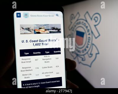 Personne tenant le smartphone avec la page Web de la Garde côtière des États-Unis (USCG) devant le sceau. Concentrez-vous sur le centre de l'écran du téléphone. Banque D'Images