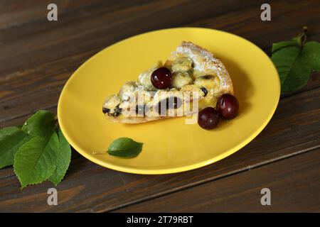 Délicieuse tarte quiche avec garniture aux cerises sur une assiette jaune Banque D'Images