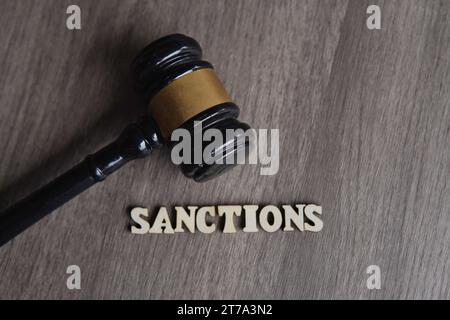 Image rapprochée du marteau du juge et texte DES SANCTIONS sur la table en bois. Banque D'Images