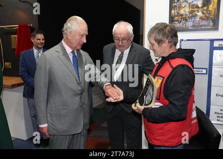 Le roi Charles III, achète une copie de The Big issue au vendeur Kelvin avec Lord John Bird, le fondateur de The Big issue, au lancement du Coronation Food Project, qui vise à combler le fossé entre le gaspillage alimentaire et les besoins alimentaires dans les quatre nations du Royaume-Uni, au centre de distribution de surplus de nourriture de South Oxfordshire Food and Education Alliance (SOFEA), à Didcot, Oxfordshire. Date de la photo : mardi 14 novembre 2023. Banque D'Images