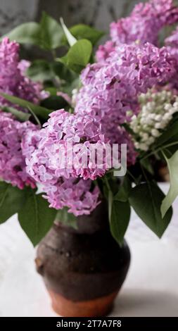 Un vase de fleurs lilas sur une table. Bouquet de lilas dans un vase en céramique sur la table. Banque D'Images