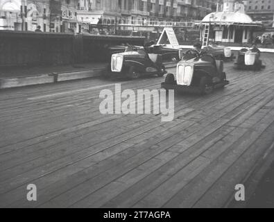 Les années 1950, des jeunes amateurs de voitures « dogem » électriques ou de karting, sur une piste en bois dans une station balnéaire victorienne, en Angleterre, au Royaume-Uni, peut-être à Great Yarmouth. Banque D'Images