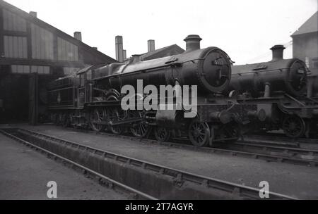 Années 1950, historique, deux locomotives à vapeur de l'époque à l'extérieur d'un hangar de chemin de fer, Angleterre, Royaume-Uni. Le numéro 5959 était une locomotive 4-6-0 GWR 'Mawley Hall' qui est entrée en service en 1936. Il a été retiré en 1962. À côté, une locomotive GWR 9306, une Churchward 2-6-0 qui entra en service en 1932. Banque D'Images