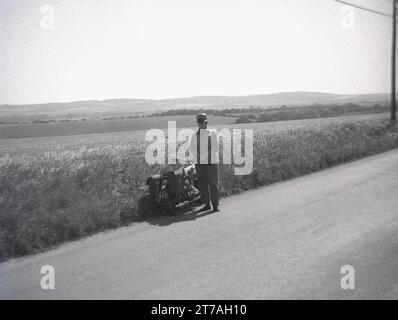 Années 1950, historique, un motocycliste masculin s'est arrêté sur une route de campagne avec sa moto aérienne (JYL 947) avec des jumelles pour admirer les vues de la campagne, en particulier le Osmington Chalk Horse & Rider sur la colline, Angleterre, Royaume-Uni, googles Banque D'Images