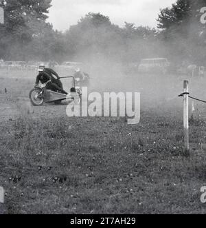 Années 1960, historique, concurrents, poussière qui s'écoule lors d'un side-car sur gazon speedway, Angleterre, Royaume-Uni. Banque D'Images