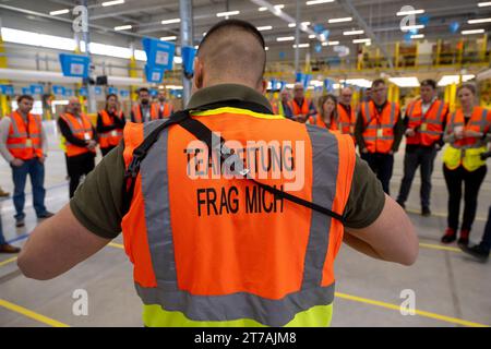 Erding, Allemagne. 14 novembre 2023. Un employé d'Amazon explique les processus dans l'établissement lors de l'ouverture officielle du centre de tri Amazon à Erding. Crédit : Peter Kneffel/dpa/Alamy Live News Banque D'Images