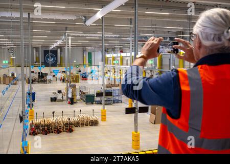 Erding, Allemagne. 14 novembre 2023. Un homme prend une photo de la salle de transbordement lors de l’ouverture officielle du centre de tri Amazon à Erding. Crédit : Peter Kneffel/dpa/Alamy Live News Banque D'Images