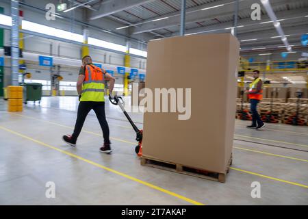 Erding, Allemagne. 14 novembre 2023. Un employé d’Amazon transporte des marchandises dans l’entrepôt lors de l’ouverture officielle du centre de tri Amazon à Erding. Crédit : Peter Kneffel/dpa/Alamy Live News Banque D'Images