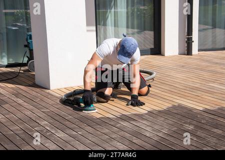 Rénovation de la terrasse Ipe patinée, homme de restauration nettoyant patine gris argenté sur la terrasse patio de la maison, Banque D'Images