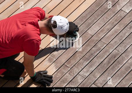 Homme ponçant la surface rugueuse et grise altérée, les planches de pont avant et après Banque D'Images