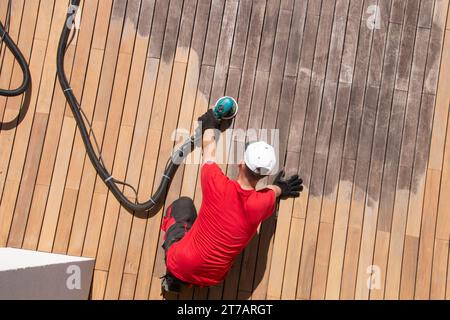 Entretien de la terrasse en bois vue de dessus, homme ponçant et nettoyant la terrasse en bois Banque D'Images