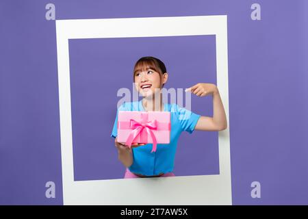 Photo de la belle femme millénaire asiatique ne blog tenir la boîte-cadeau isolée sur fond de couleur Banque D'Images