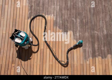 Équipement professionnel de rénovation de terrasse en bois, ponceuse électrique orbitale et collecteur de poussière sur terrasse ipe Banque D'Images