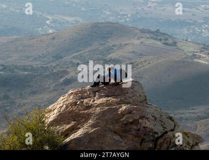 Un jeune couple regarde depuis un affleurement rocheux au-dessus de la baie de Lara, parc national d'Akamas, péninsule d'Akamas, Chypre Banque D'Images