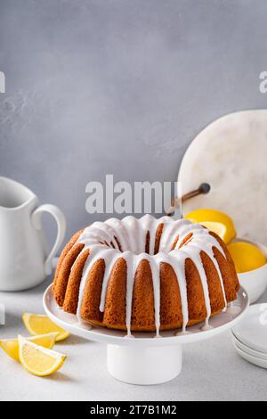 Gâteau bundt au citron avec glaçage vanille en poudre de sucre sur un support à gâteau Banque D'Images