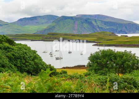 Île de Canna dans les Hébrides intérieures, Écosse. Un port tranquille avec des yachts amarrés et la plus grande île de Rum en arrière-plan. Horizontal. Copier Banque D'Images